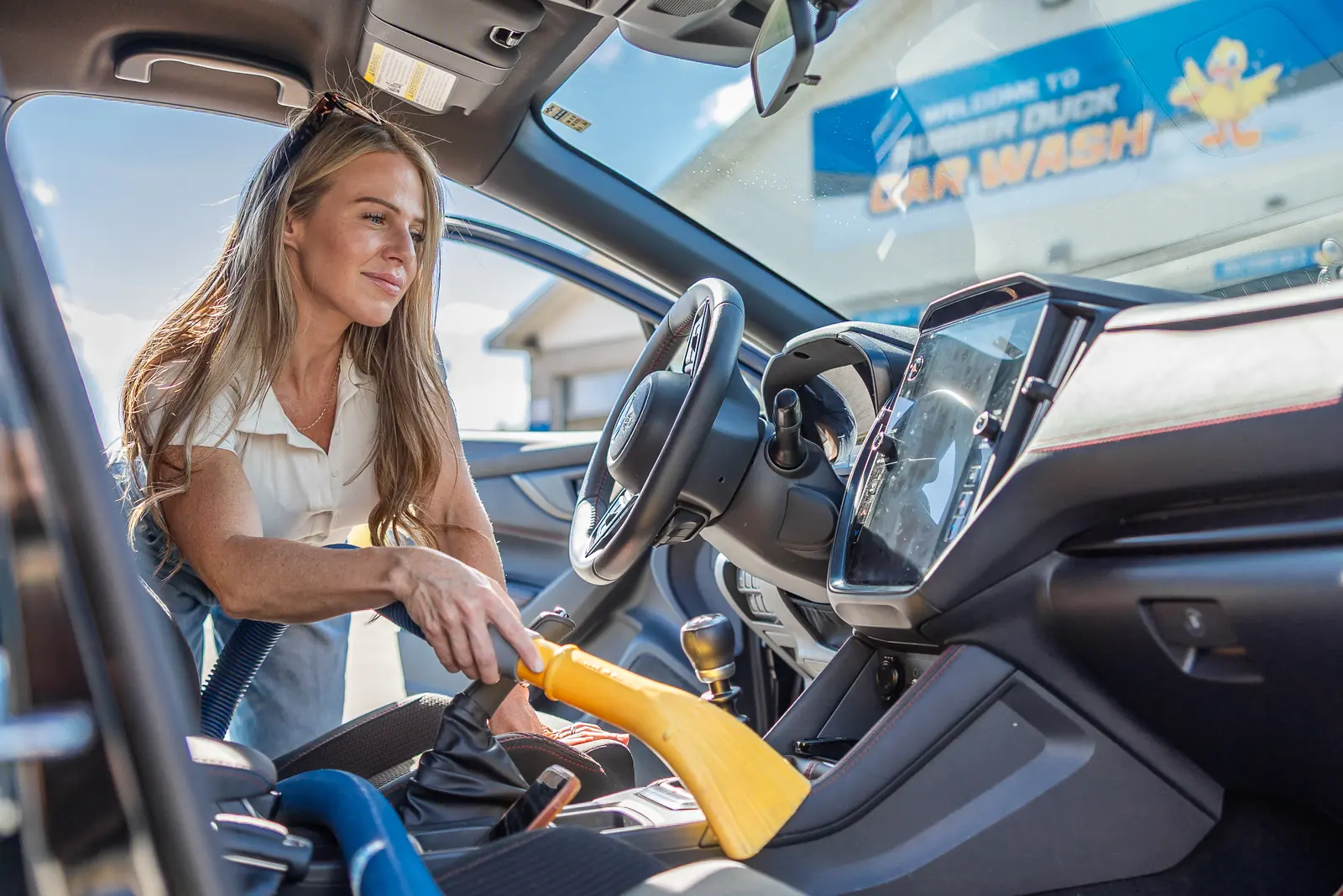 A customer vacuuming the inside of her car at a Rubber Duck vacuum station